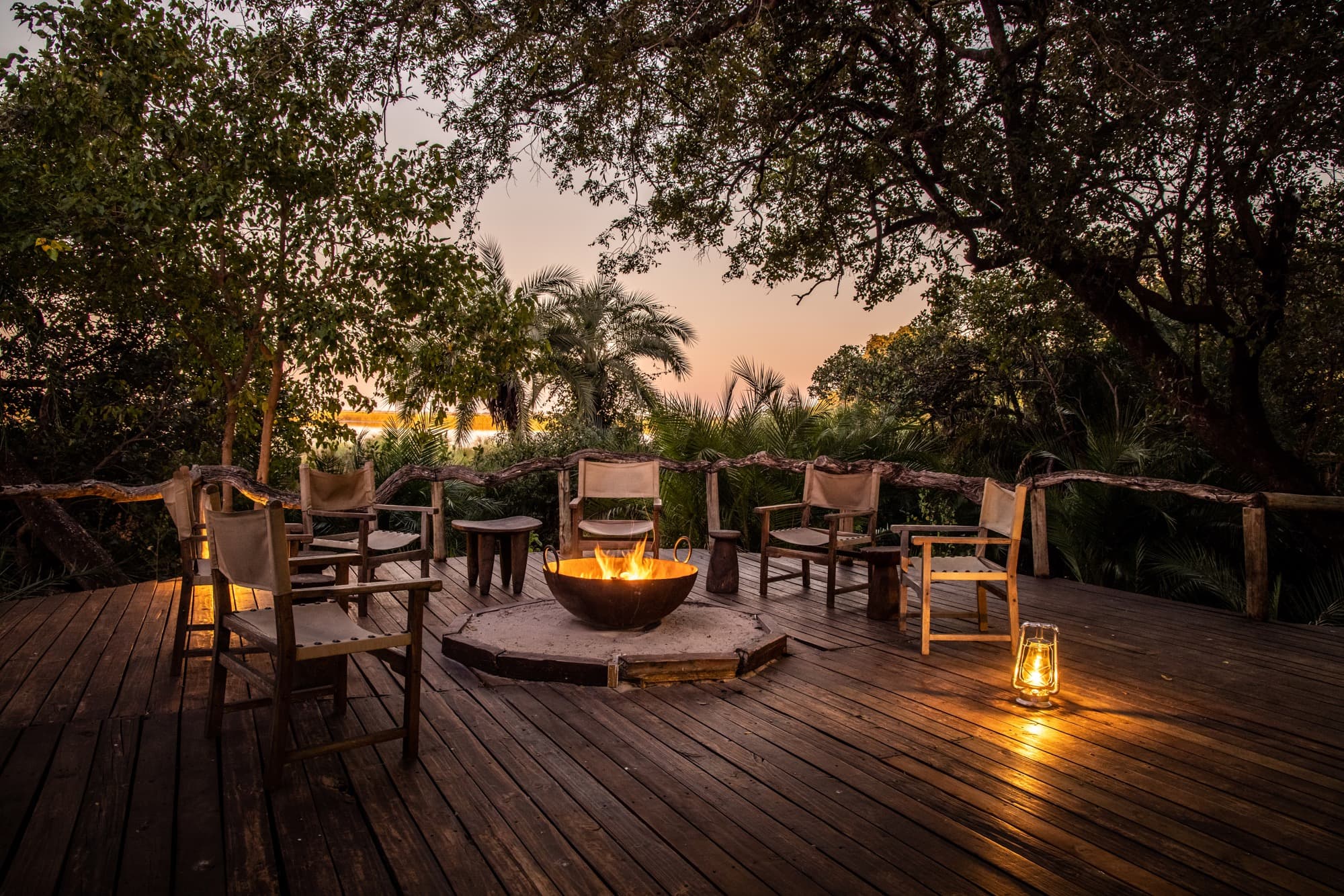 Chairs drawn around a lodge firepit at dusk