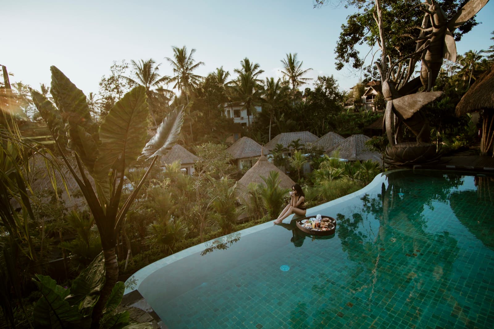 A hillside villa pool above the palms, breakfast floating on the water